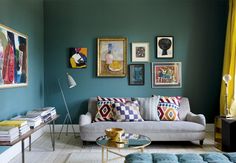 a living room with blue walls and pictures on the wall above it's couch