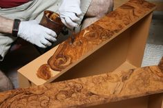 a man in white gloves working on a piece of wood