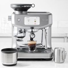 an espresso machine sitting on top of a counter next to a coffee cup