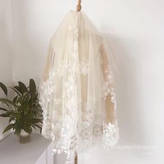 a white dress on a mannequin next to a potted plant in a corner