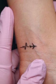 a small heartbeat tattoo on the ankle with an arrow and heart beat symbol in black ink