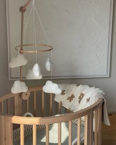 a wooden crib with white clouds hanging from it's sides in a room