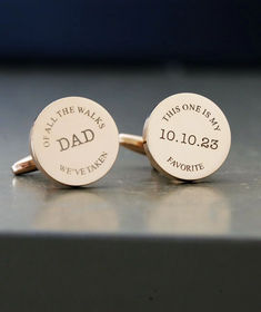 two personalized cufflinks with names and date engraved on the back, sitting on a table