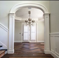 an entry way with white walls and wood flooring in the center is flanked by two wooden banisters