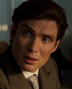 a close up of a person in a suit and tie looking at the camera with an intense look on his face