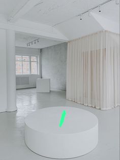 an empty white room with curtains on the wall and a round table in the middle