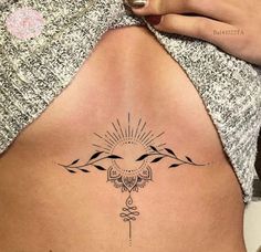 a woman's back with a tattoo design on her stomach and the sun above it