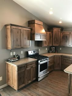 an empty kitchen with wooden cabinets and stainless steel stove top oven in the center island