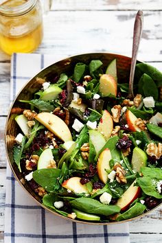 a salad with spinach, apples, walnuts and feta cheese in a bowl