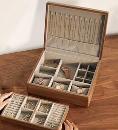 an open wooden jewelry box on a table with two women's hands holding it