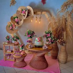 a table topped with cakes and flowers next to vases filled with plants on top of a pink rug