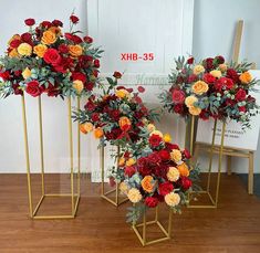 three gold vases with flowers in them on a wooden floor