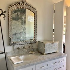 a bathroom with marble counter tops and white cabinets, along with a large mirror over the sink