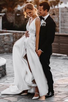 a man and woman in formal wear standing next to each other on a stone walkway