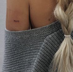 the back of a woman's shoulder with a small tattoo on her left arm