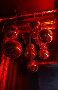 disco ball lights hanging from the ceiling in a dark room with red light shining on them