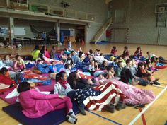 a large group of people sitting on the floor in a gym with american flag blankets