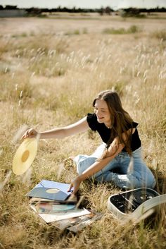 a woman sitting on the ground with a frisbee in her hand next to books