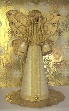 an angel statue with gold wings on a white tablecloth and snowflakes in the background