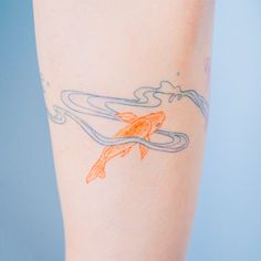 a woman's leg with an orange fish tattoo on her left arm and blue background