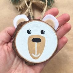 a hand holding a wooden ornament with a bear face on it's side