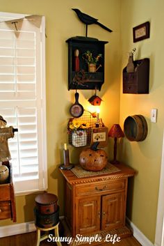 an old fashioned cabinet is in the corner of a room with yellow walls and white shutters