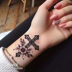 a woman's arm with a cross and flowers tattoo on her left side wrist