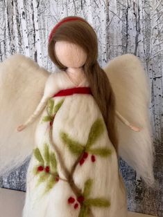 an angel figurine with white wings and green leaves on it's body