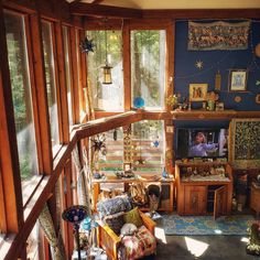 a living room filled with furniture and lots of windows next to a wooden wall covered in pictures