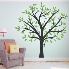 a living room with a chair and tree wall decal