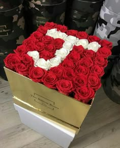 a box filled with red and white roses in the shape of a letter v on top of a wooden floor