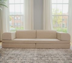 a beige couch sitting in front of two windows