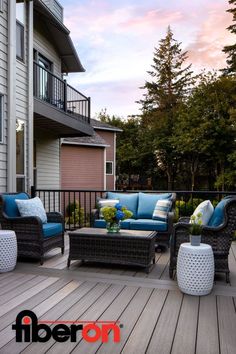 an outdoor patio with wicker furniture and blue cushions on the wooden decking area