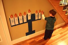 a young boy standing in front of a wall with candles on it