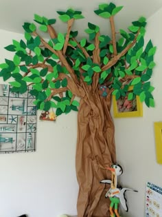 a tree made out of brown paper with green leaves and a stuffed animal in the middle