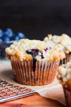 blueberry muffins with crumbled toppings on a wooden cutting board