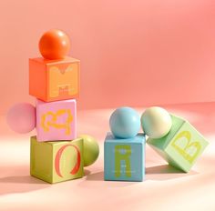 an assortment of colorful blocks and balls in front of a pink background with the letter d on top