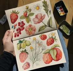 a person is painting flowers and berries on paper