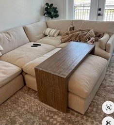 a large sectional couch in a living room with pillows on it's back end