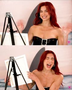 a woman with red hair is smiling and holding an easel in front of her face