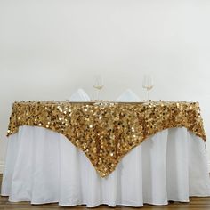 a table with gold sequins on it and two wine glasses at the top