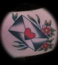 an envelope with a heart and flowers on the side of her stomach is seen in this tattoo design