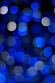 blue and white lights are shining in the dark night sky, as well as blurry circles