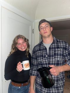 a man and woman standing next to each other holding coffee mugs