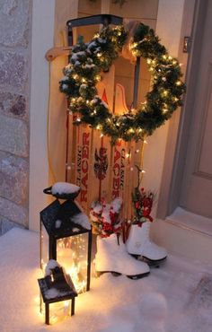 a snow covered front door with a wreath and lights in the snow next to it