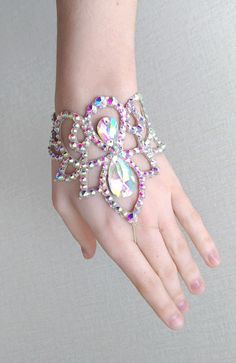 a woman's hand wearing a bracelet with jewels and pearls on the ring finger