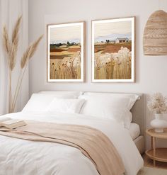 two paintings on the wall above a bed in a room with white sheets and pillows