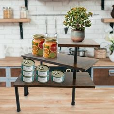 three tiered table with canned food on it in a kitchen next to a potted plant