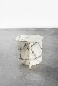 a marble coffee table on concrete flooring with white walls in the background and grey floors