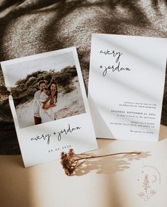 two wedding cards with the same photo on them are laying next to each other and one is holding a dried flower